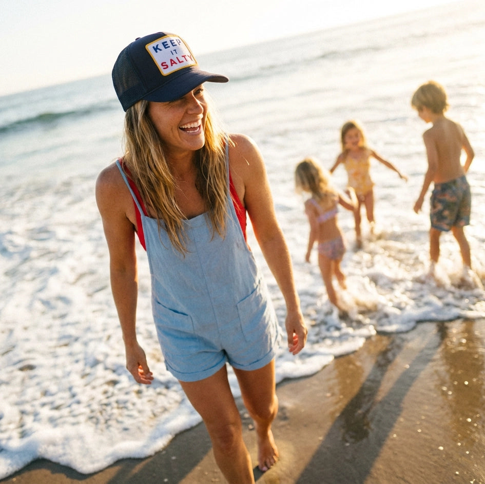 Woman walking on a beach with children playing in the water