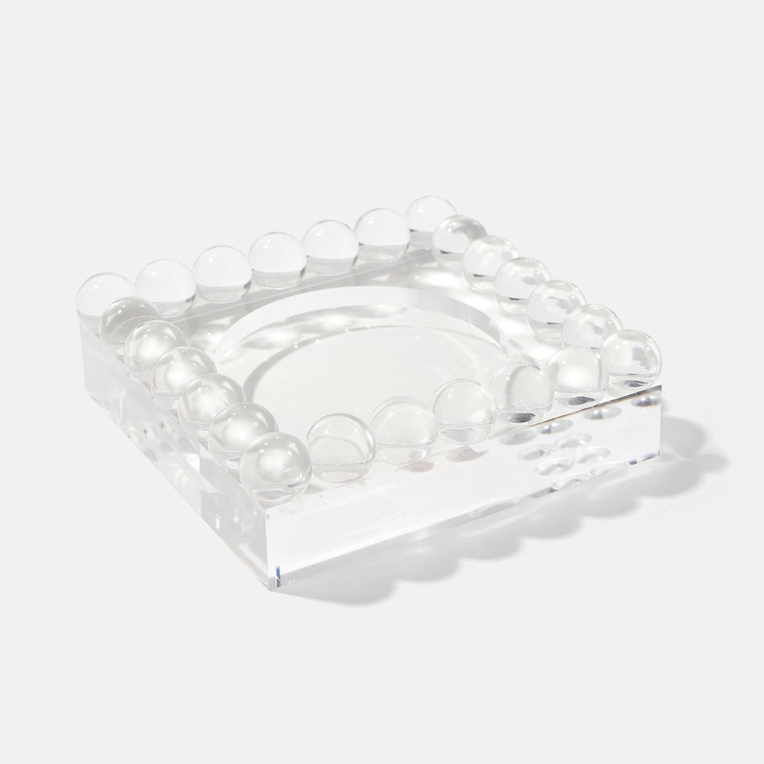 Clear square glass object with embedded round elements on a white background