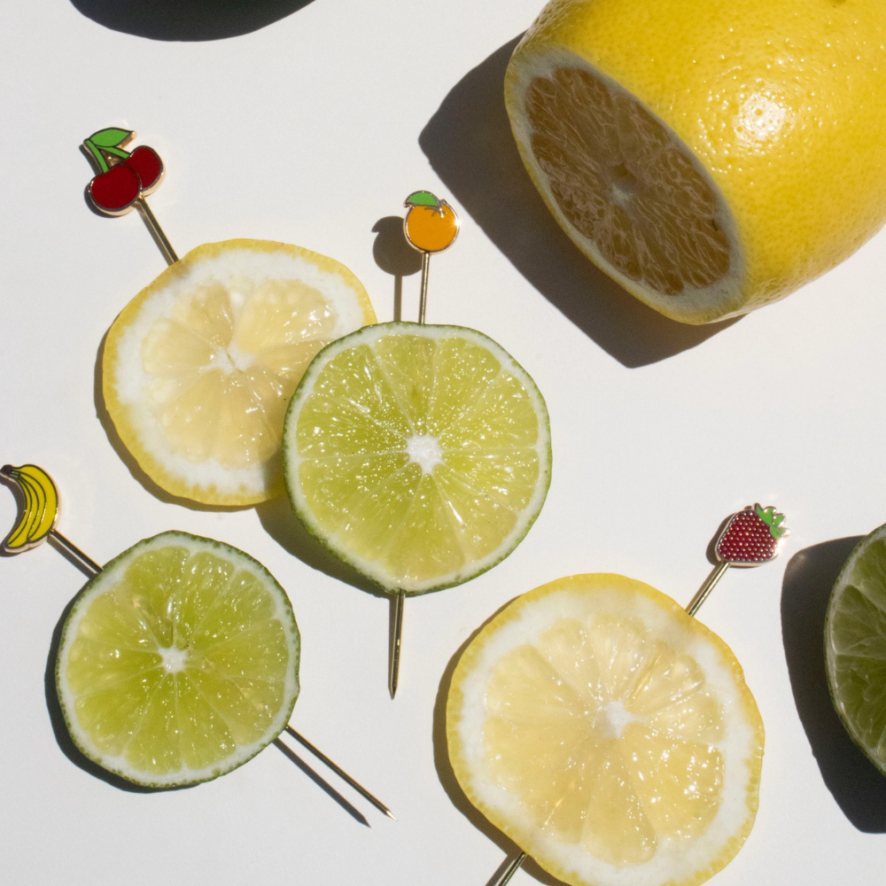 Sliced lemons and limes on skewers with decorative ends on a white background