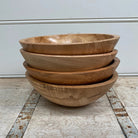 Stack of wooden bowls on a wooden floor with a white wall background