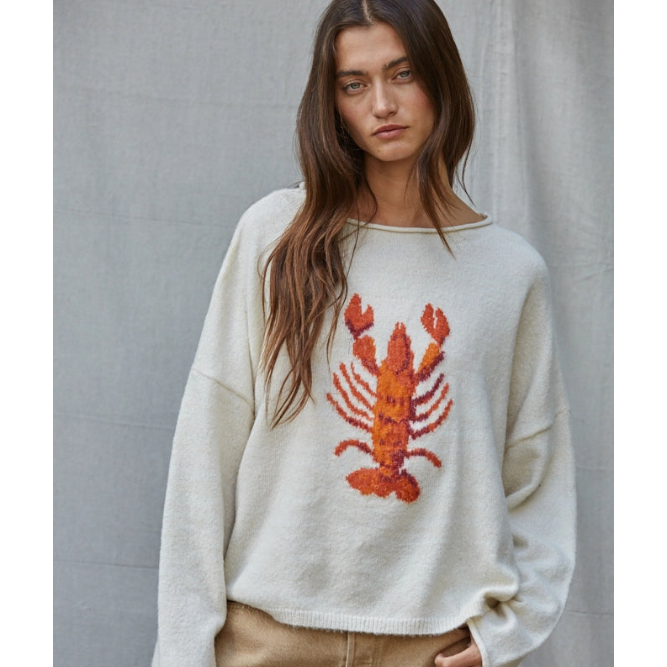 Woman wearing a sweater with a lobster design against a plain background